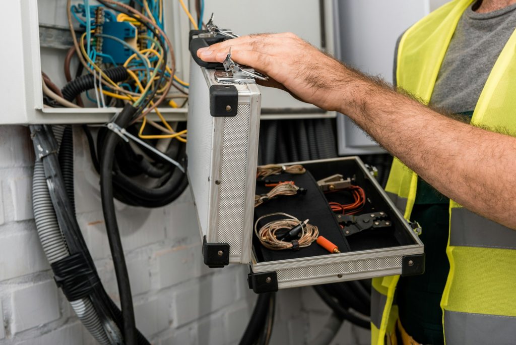 cropped-image-of-electrician-holding-toolbox-near-electrical-box-in-corridor.jpg